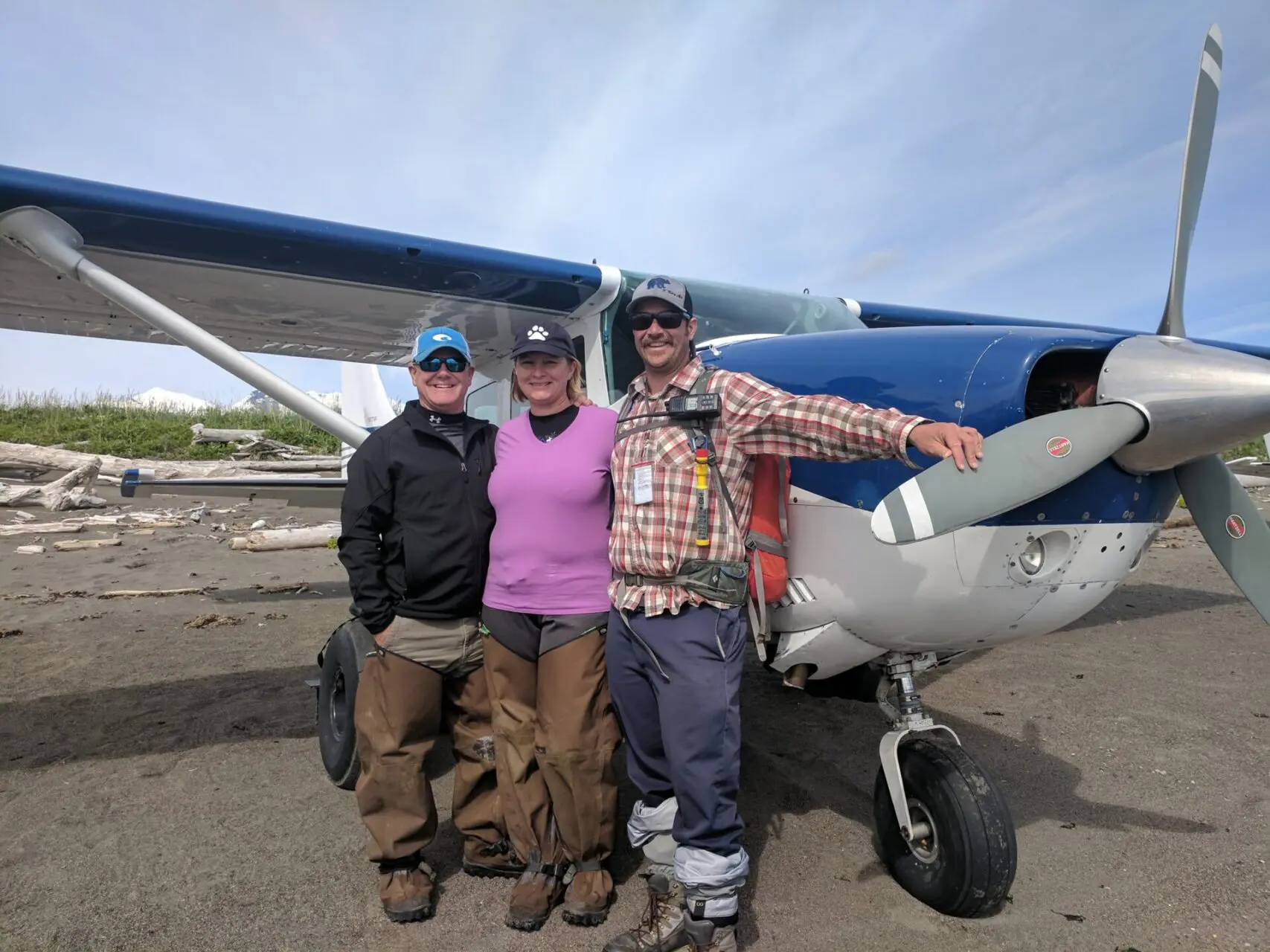 Three people standing in front of a small plane.